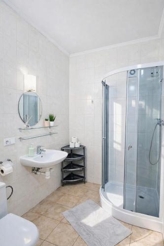 a white bathroom with a shower and a sink at Best Two Room Apartment in Mukacheve