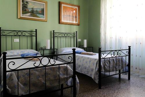 2 camas en un dormitorio con paredes verdes en Guesthouse Stazione Pisa Centro, en Pisa