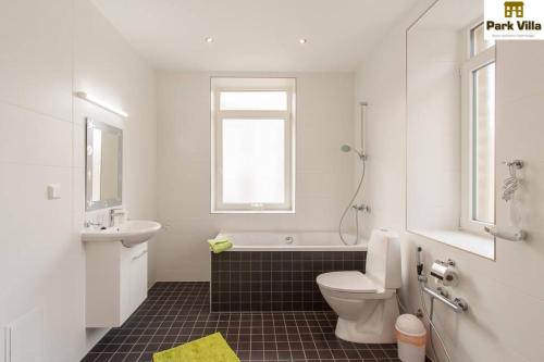 a white bathroom with a toilet and a sink at Park Villa Apartments in Bad Kissingen