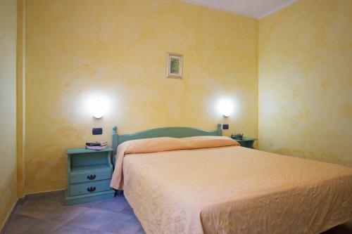a bedroom with a bed and a blue nightstand with two lamps at Albergo Residenziale Gli Ontani in Cala Liberotto