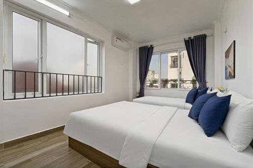 a white bedroom with a large bed with blue pillows at Miah Ha Noi Hotel - the best choice in Hà Nội Old Quarter in Hanoi