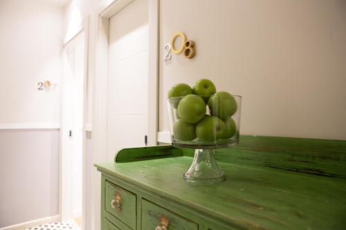 a bowl of green apples sitting on top of a dresser at Jacob Shenkin Hotel in Tel Aviv