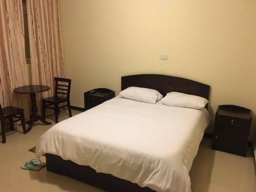een slaapkamer met een bed met 2 kussens en een tafel bij Cheers Bed & Breakfast in Addis Ababa