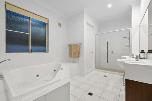 a white bathroom with a tub and a sink at Surfmist by the Beach Pet Friendly with Pool in Kingscliff