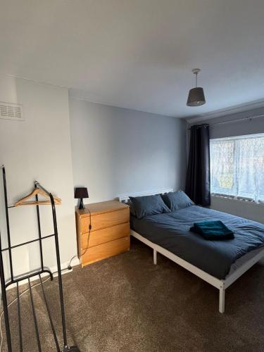 a bedroom with a bed and a dresser and a window at Jerry's lane 3 bed house free parking free wifi in Birmingham