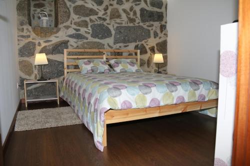a bedroom with a wooden bed with a stone wall at Quinta da Costa in Lixa