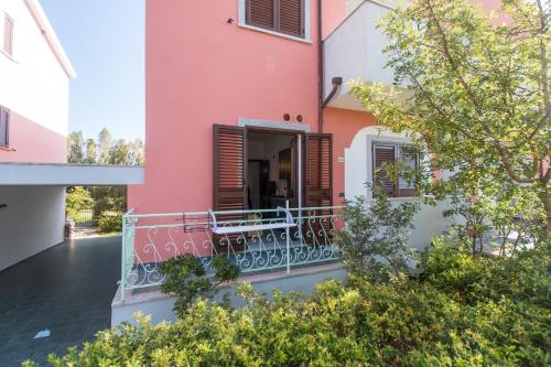 a pink and white house with a balcony at Albergo Residenziale Gli Ontani in Cala Liberotto