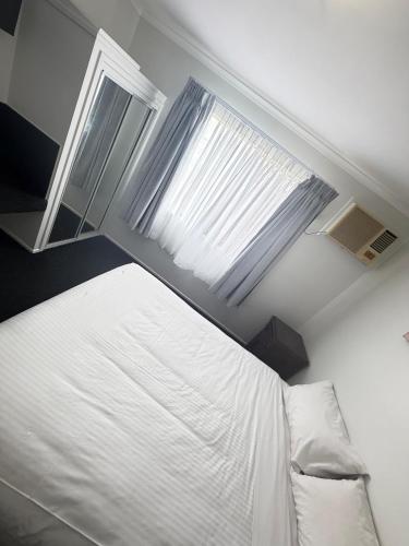 a bedroom with a white bed and two windows at Centrepoint Motor Inn in Rockhampton