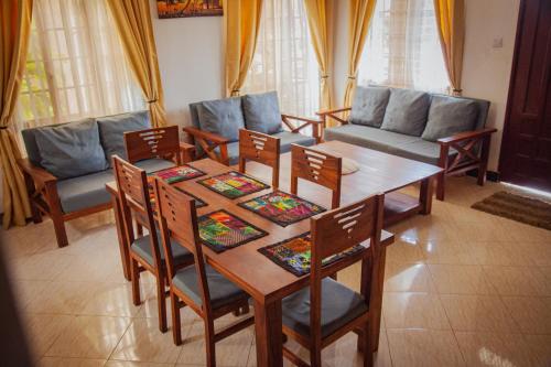un soggiorno con tavolo e sedie in legno di Makinihomestay ad Arusha