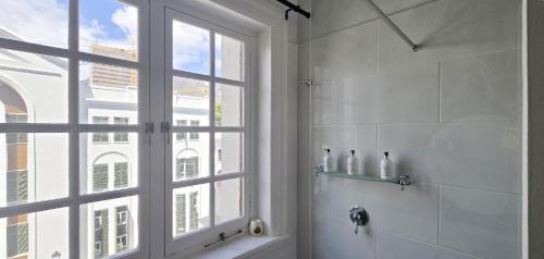 a white bathroom with a window and a shower at The Cape Town Club in Cape Town
