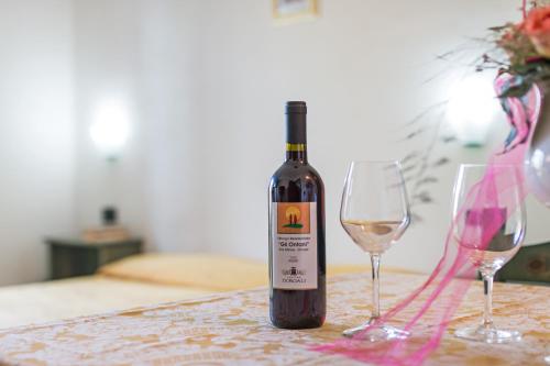 a bottle of wine sitting on a table with two glasses at Albergo Residenziale Gli Ontani in Cala Liberotto