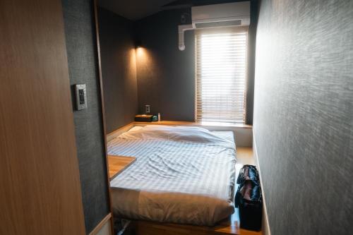 a small bedroom with a bed and a window at Yumoto Station Hotel MIRAHAKONE in Hakone