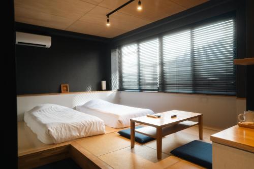 a bedroom with a bed and a table and a window at Yumoto Station Hotel MIRAHAKONE in Hakone