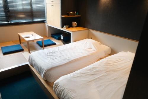 a room with two beds and a table and a desk at Yumoto Station Hotel MIRAHAKONE in Hakone
