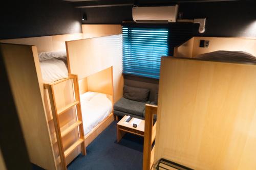 a small room with two bunk beds and a window at Yumoto Station Hotel MIRAHAKONE in Hakone