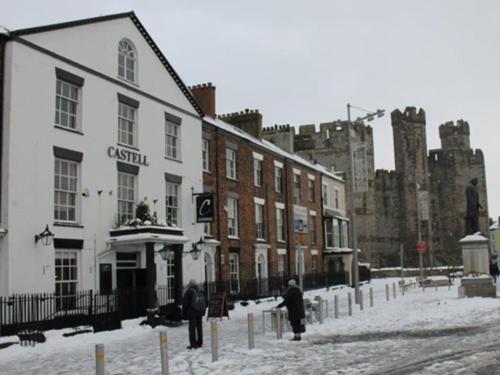 a snow covered street in front of a castle at Y Castell in Caernarfon