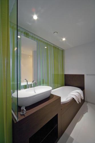 a bathroom with a tub and a sink and a mirror at Parkhotel Roeselare in Roeselare