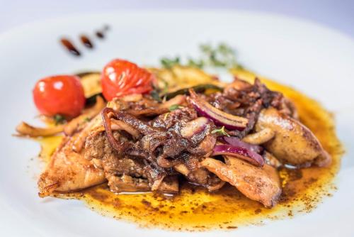 a plate of food with meat and tomatoes on it at Rezort u Bobiho in Nový Tekov