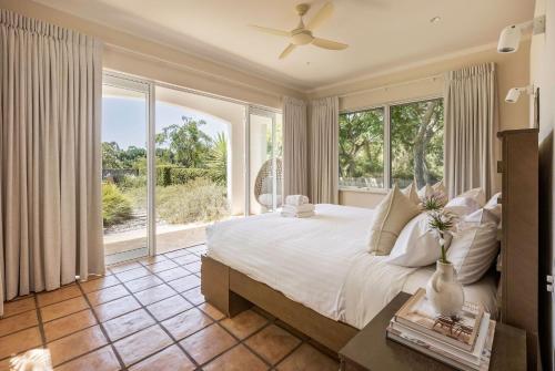 a bedroom with a large bed and large windows at Meelup Vista in Dunsborough