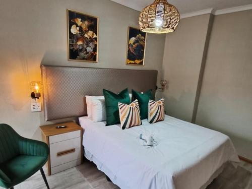 a bedroom with a bed with green pillows and a green chair at Nu Oasis guest house in Johannesburg