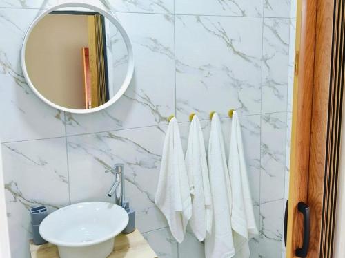 a bathroom with white marble walls and a mirror at Nu Oasis guest house in Johannesburg