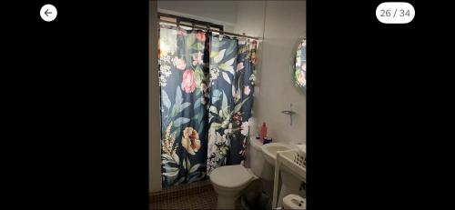 a bathroom with a toilet and a shower curtain with flowers at Cómoda y céntrica habitación en Tenochtitlán, en departamento compartido, CDMX in Mexico City