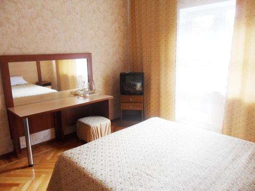 a hotel room with a bed and a desk and a television at Hotel Uiut in Nalchik