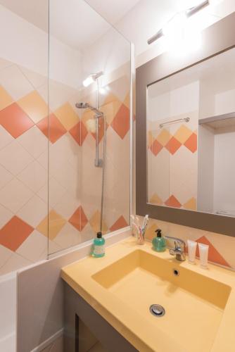 une salle de bain avec un lavabo et un miroir dans l'établissement Résidence Promenade des Bains - maeva Home, à Saint-Raphaël
