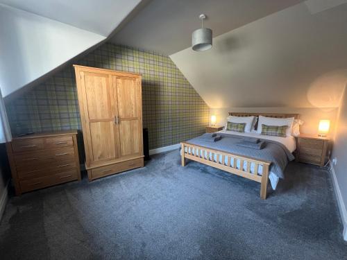 a bedroom with a large bed and a wooden cabinet at PERGOLA Cottage in Melrose