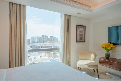 a bedroom with a bed and a chair and a large window at Cheval Maison - Expo City Dubai in Dubai