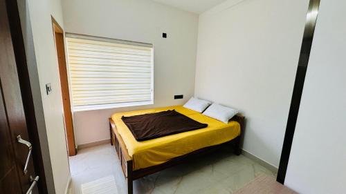 a small bedroom with a yellow bed with a window at Sign Valley in Cochin