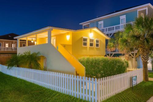 a yellow house with a white fence in front of it at Four Bedroom Two Level Home Near Beach in South Padre Island