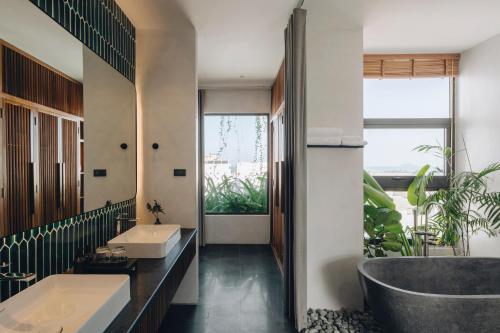 a bathroom with a tub and a large window at Le Mint Hotel Quy Nhơn in Quy Nhon