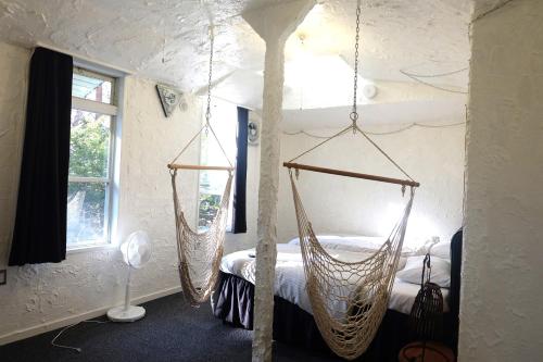 two hanging hammocks in a room with a bed at はじまりの宿 ディール in Tsumagoi