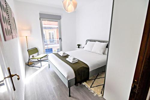 a bedroom with a bed and a chair and a window at Contemporary Chic with Terrace & Balcony in Madrid