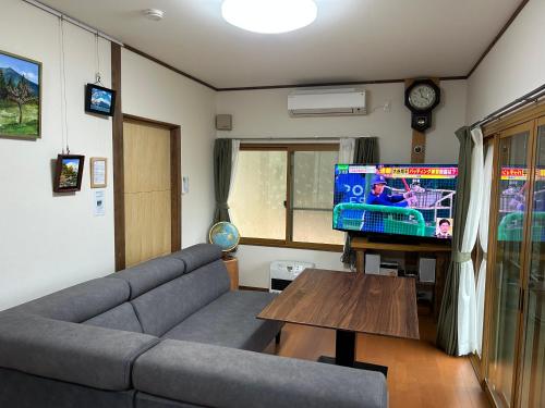 a living room with a couch and a flat screen tv at ANBAEE Private Mountain Villa あんばええ in Nakatsugawa