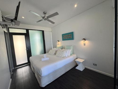 a bedroom with a white bed with a ceiling fan at Esperance Waterfront Apartment in Esperance