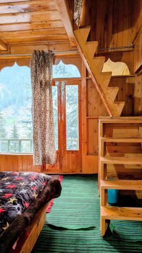 a bedroom with a bed and a window in a cabin at The Tree Hub Jibhi in Jibhi