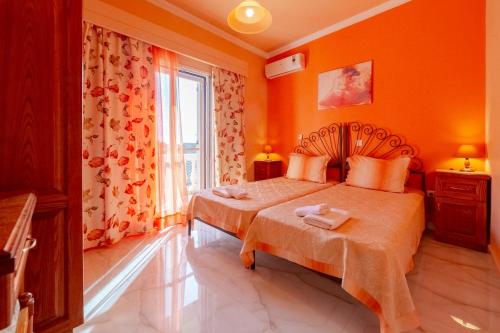a bedroom with two beds with orange walls and a window at Seafront Apartment with Panoramic Rooftop Terrace in Paramonas