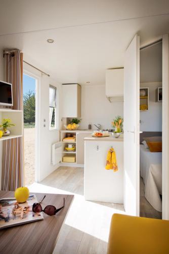 a kitchen with white cabinets and a living room at Vakantiepark Koningshof in Rijnsburg