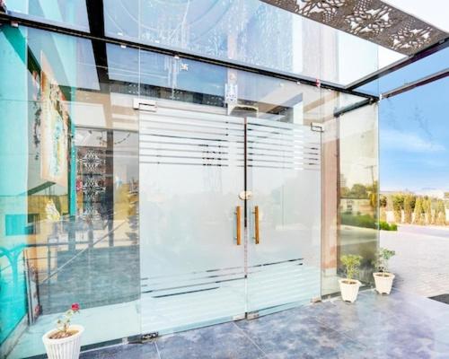 a glass door of a building with two potted plants at Hotel Aroma Regency in Meerut