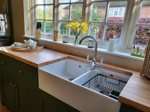 a kitchen with a large white sink and windows at Freshwater Barn in Benenden