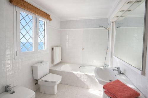 a white bathroom with a tub and a toilet and a sink at Auba Mar - Alcudia Sea View in Alcudia
