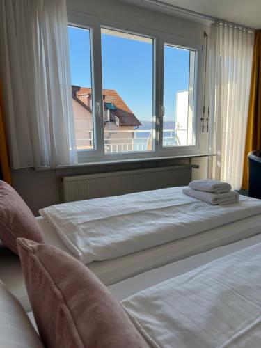a bedroom with two beds and a large window at Hotel Capri in Überlingen