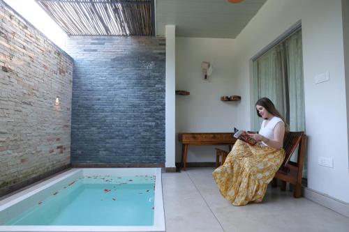 a woman sitting in a chair next to a swimming pool at B Town Resort Near Infopark Kakkanad in Kakkanad