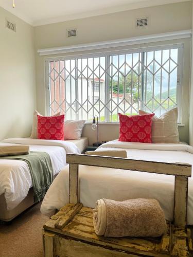 a bedroom with two beds with red pillows and a window at Salt & Still in Freeland Park