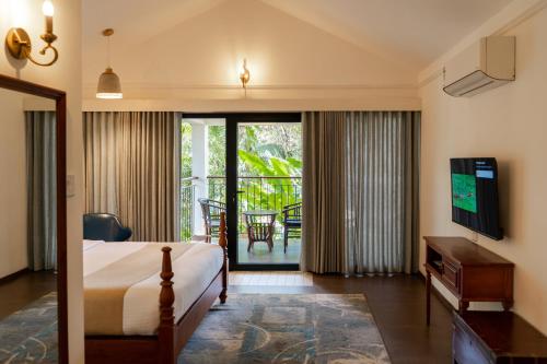 a bedroom with a bed and a television and a balcony at Willow Resorts Wayanad in Ambalavayal