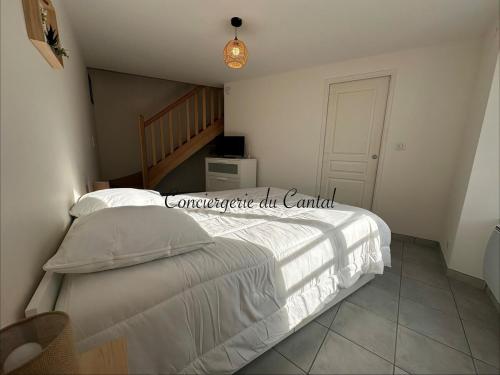 a bedroom with a white bed and a staircase at Murat - La petite maison Murataise in Murat