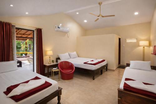 a hotel room with two beds and a red chair at Megha Resort , Hampi in Hampi