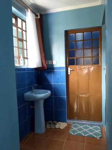 a blue bathroom with a sink and a door at SQ Acacia in Langata Rongai